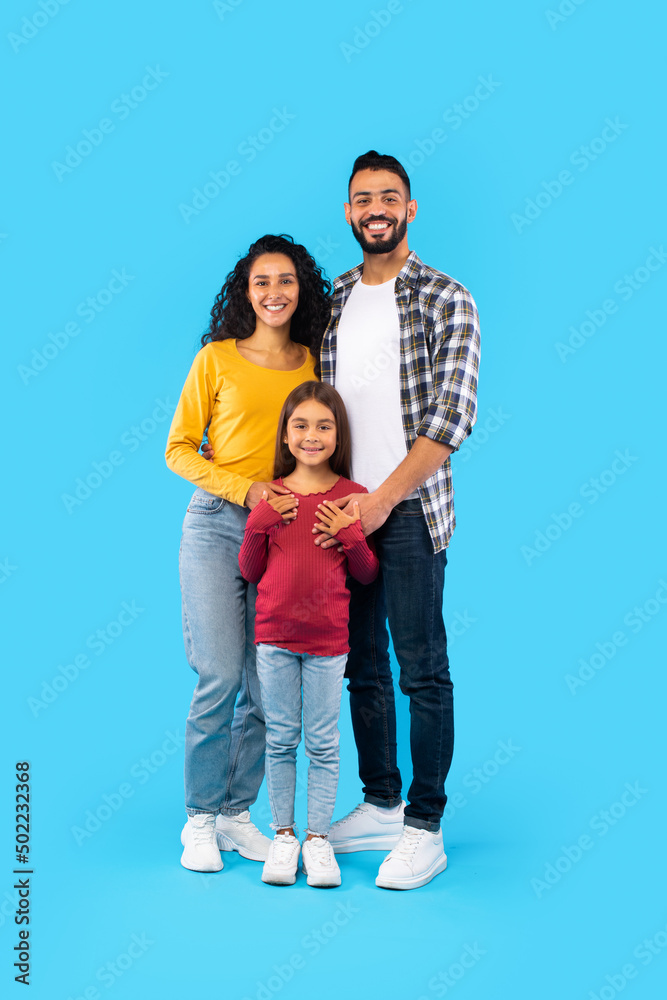 Cheerful Arabic Family Of Three Posing Embracing, Blue Background, Vertical Cheerful Arabic Family Of Three Posing Embracing, Blue Background, Vertical