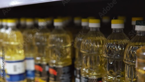 Young man alarmist buys sunflower oil in supermarket. Close up of male taking many sunflower oil bottles at grocery store. Sunflower oil shortage in Europe. photo