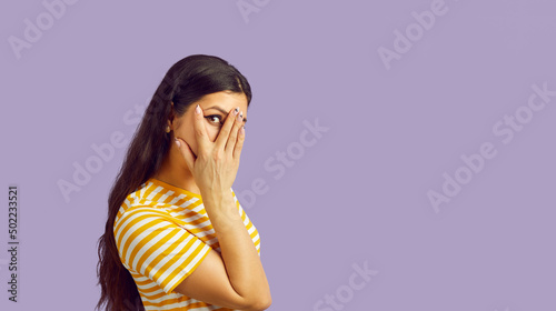 Obraz na plátně Funny ethnic girl isolated on purple studio background cover face peek with spy eye