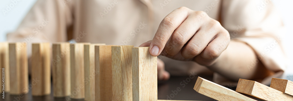 Businesswoman stops hands falling over domino to stop risk continuously, Continuous damage reduction, Stop business domino failures concept. Businesswoman stops hands falling over domino to stop risk continuously, Continuous damage reduction, Stop business domino failures concept.