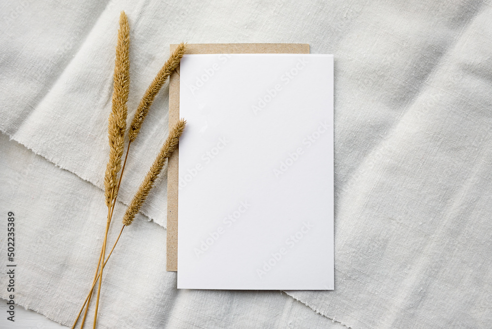 Stock stationery mock-up scene in a light key. Empty vertical greeting card and dried grains on white linen background. Stock stationery mock-up scene in a light key. Empty vertical greeting card and dried grains on white linen background.