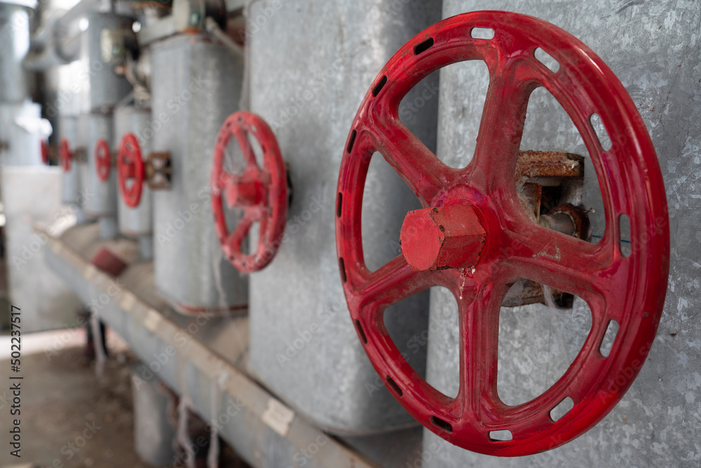 Red pipes and valve handle wheel at the abandonned ruin