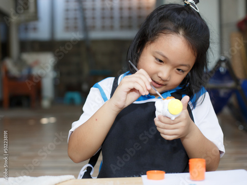 Asian girl paints on a plaster doll. Enhancing the development of imagination and art