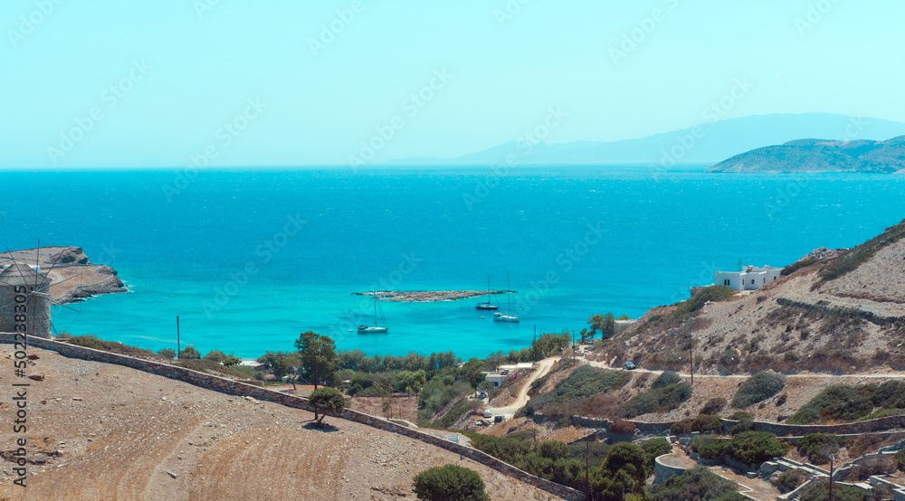 Sailing yachts or boats at anchor stop on Scninoussa island or any Greek Island in Mediterranean or Aegean sea, far horizon seascape view