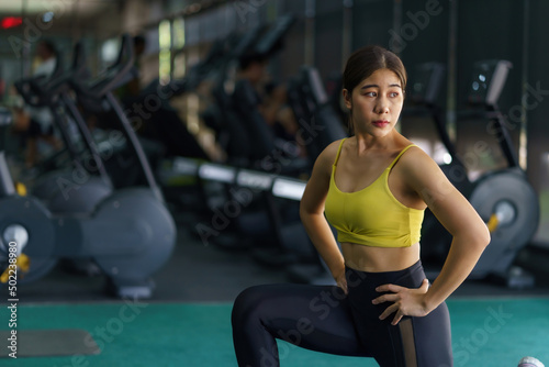 Beautiful Asian woman in sportswear is doing stretching and warming up before her workout at gym.