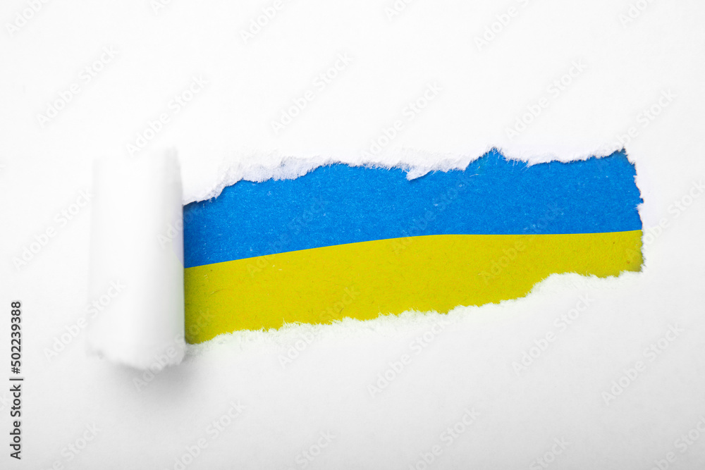 Obraz premium Ukrainian blue and yellow flag in the hole in paper