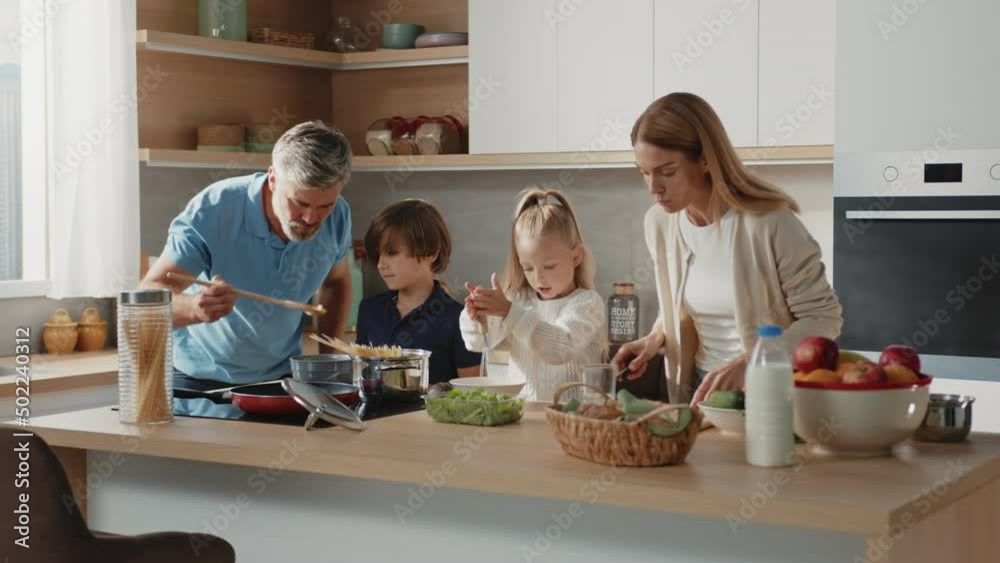 Caucasian family with little kids prepare together healthy vegetable salad in the kitchen at home. Beautiful family with little kids prepare breakfast together at home. Caucasian family with little kids prepare together healthy vegetable salad in the kitchen at home. Beautiful family with little kids prepare breakfast together at home.
