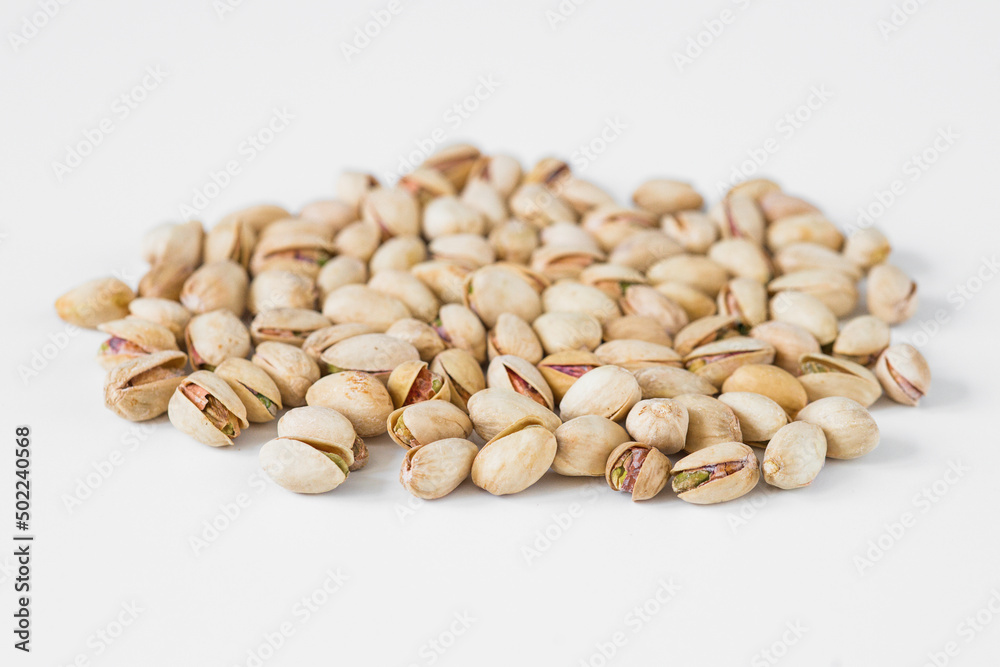 Flat lay of pistachio nuts on a white background.