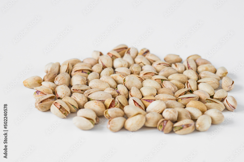 Flat lay of pistachio nuts on a white background.
