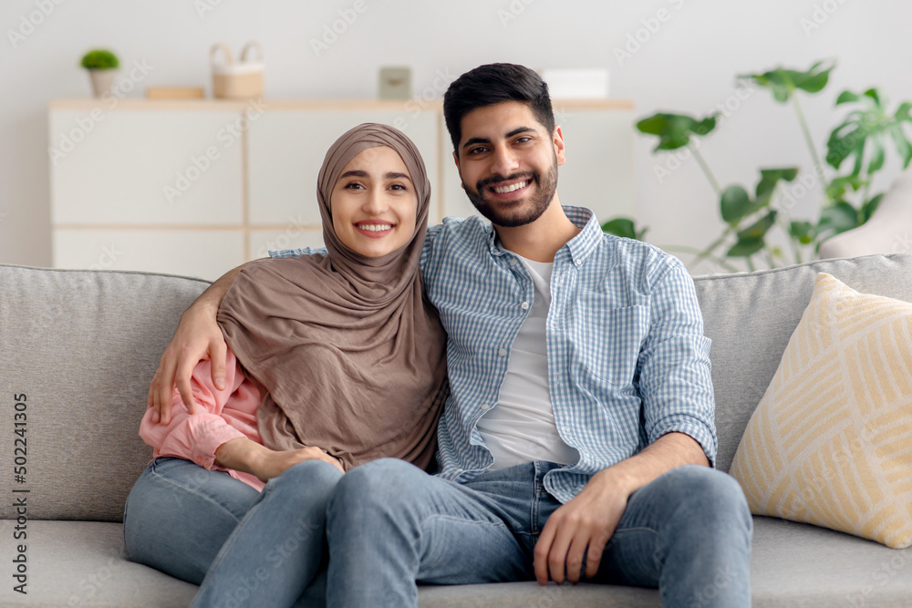 Happy Muslim Family Couple Sitting Together And Embracing At Home