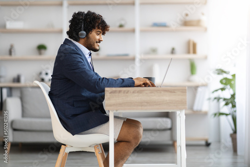 Young indian guy working from home while pandemic, copy space