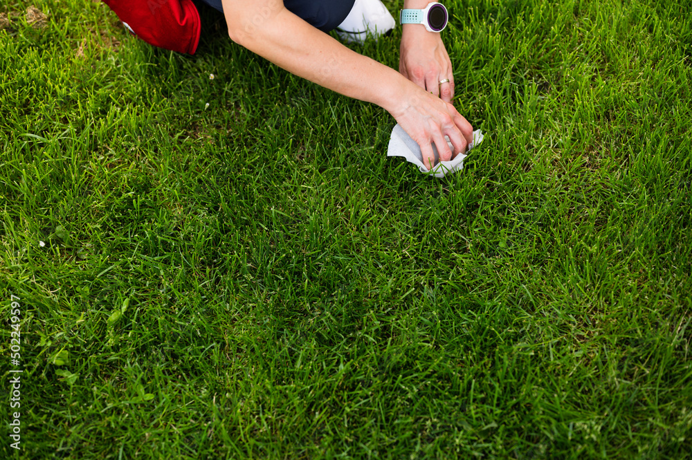 Woman in park picking up dog's poop. Female owner cleaning up after the dog. No pets visible, plenty of copy-space Woman in park picking up dog's poop. Female owner cleaning up after the dog. No pets visible, plenty of copy-space