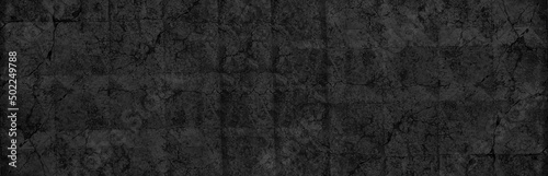 Old black concrete slab wide panoramic texture. Cracked aged cement surface large backdrop. Dark gloomy grunge abstract background