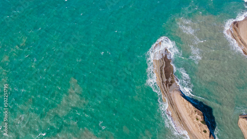 Aerial photography on the island of Corfu in Greece. Coast with rocks, turquoise sea. Top view of waves, water.