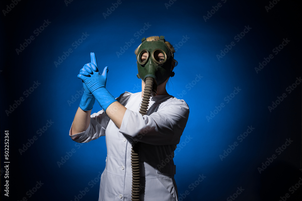 doctor woman in a gas mask folded her hands in the shape of a gun on a blue background doctor woman in a gas mask folded her hands in the shape of a gun on a blue background