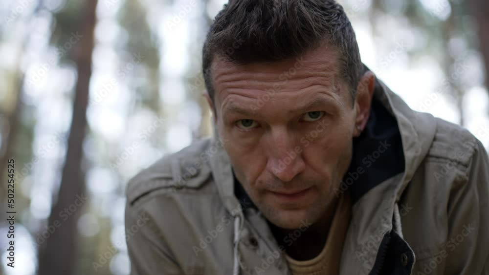 Close-up portrait of exhausted male survivor standing in forest looking at camera. Tired Caucasian adult confident man posing in wood with serious facial expression. Trips and adventures Close-up portrait of exhausted male survivor standing in forest looking at camera. Tired Caucasian adult confident man posing in wood with serious facial expression. Trips and adventures