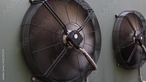 industrial air conditioner extractor fan hanging on the wall outside the building. refrigeration blower running and spinning close up