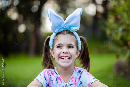 Grinning little girl with Easter bunny ears outside photo