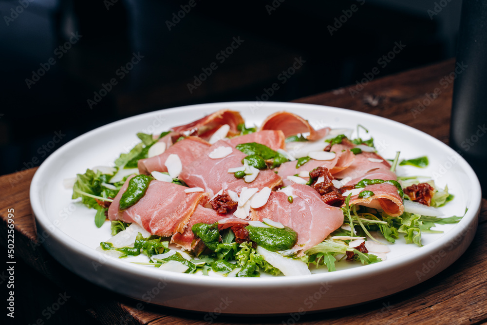salad with prosciutto and avocado with avocado sauce on a white plate