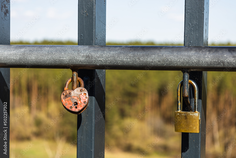 Closeup view of heart-shaped love padlock hanging on a bridge fence Closeup view of heart-shaped love padlock hanging on a bridge fence