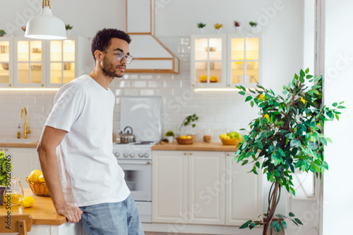 Handsome african american man in white t-shirt standing in the kitchen.
