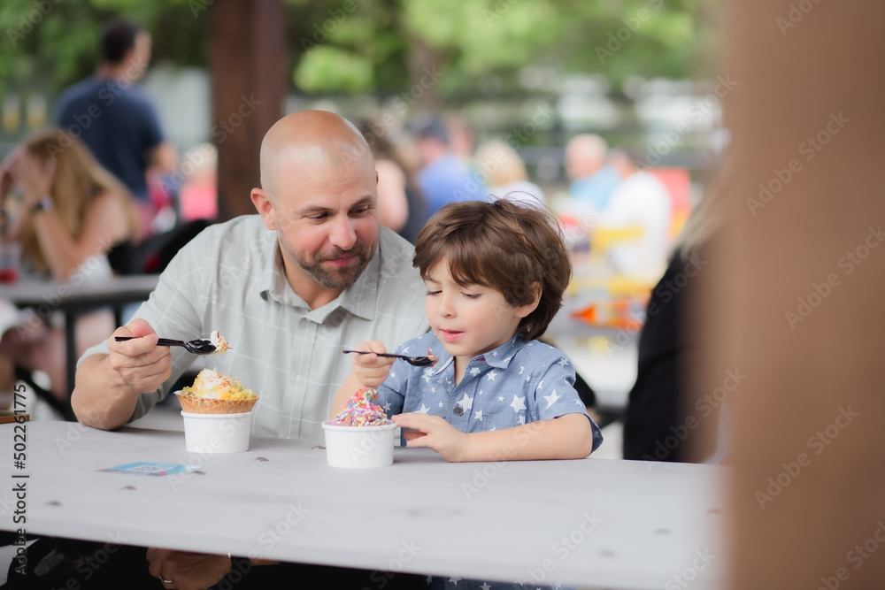 Dad and son buying and eating ice-cream in boxi parkin lake nona florida Dad and son buying and eating ice-cream in boxi parkin lake nona florida