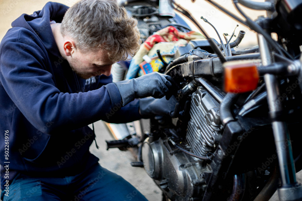 a man repairs a motorcycle, motorcycle maintenance.