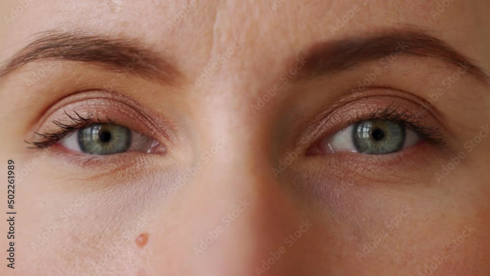 Extreme close-up of young woman opens her eyes and look at camera and open widely eyes.