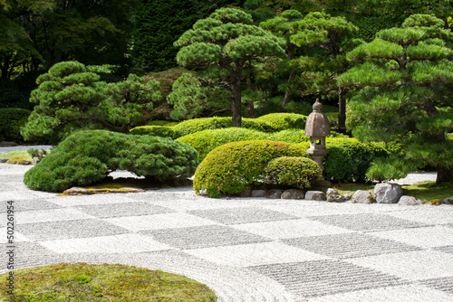 Zen garden with raked stones and green vegetation © Tamela