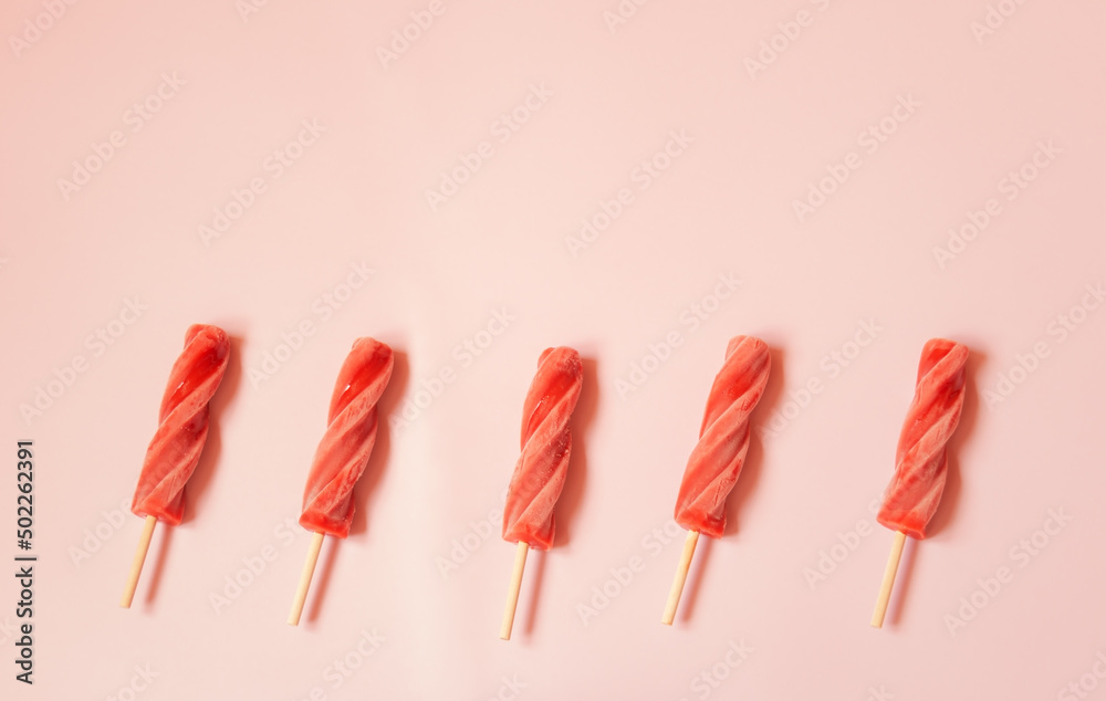 Spiral strawberry popsicles as a border on pink background. Spiral strawberry popsicles as a border on pink background.