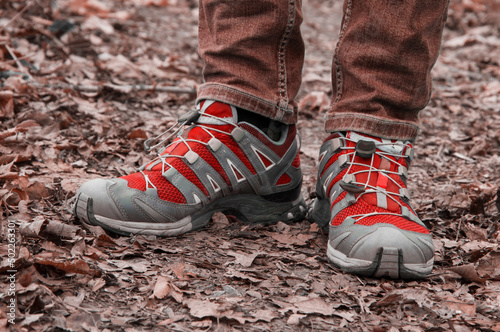 sneakers on the path. man stands with her foot in the woods. illustration of travel. red shoes on a natural background. hiking concept