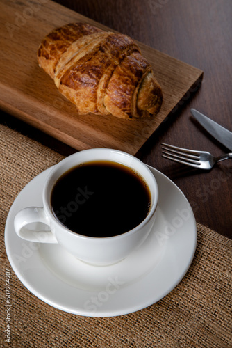 Fototapeta Naklejka Na Ścianę i Meble -  Croissant with a cup of full coffee,directly above	