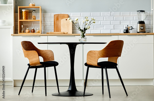 Minimal background image of black kitchen table set with two wooden chairs  copy space