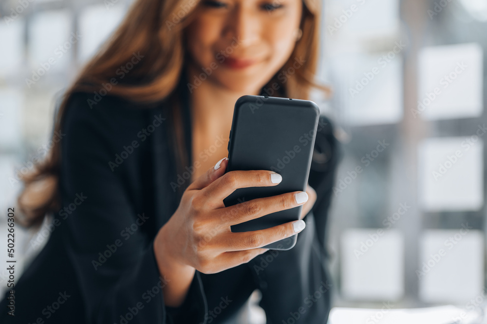 Young businesswoman looking at financial information from a mobile phone, she is checking company financial documents, she is a female executive of a startup company. Concept of financial management.