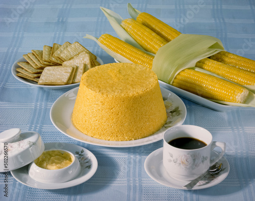 Corn couscous at the table with a cup of coffee and boiled corn cobs. Typical food from the northeast region of Brazil.