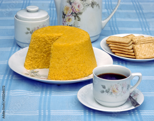Corn couscous at the table with a cup of coffee and boiled corn cobs. Typical food from the northeast region of Brazil. photo