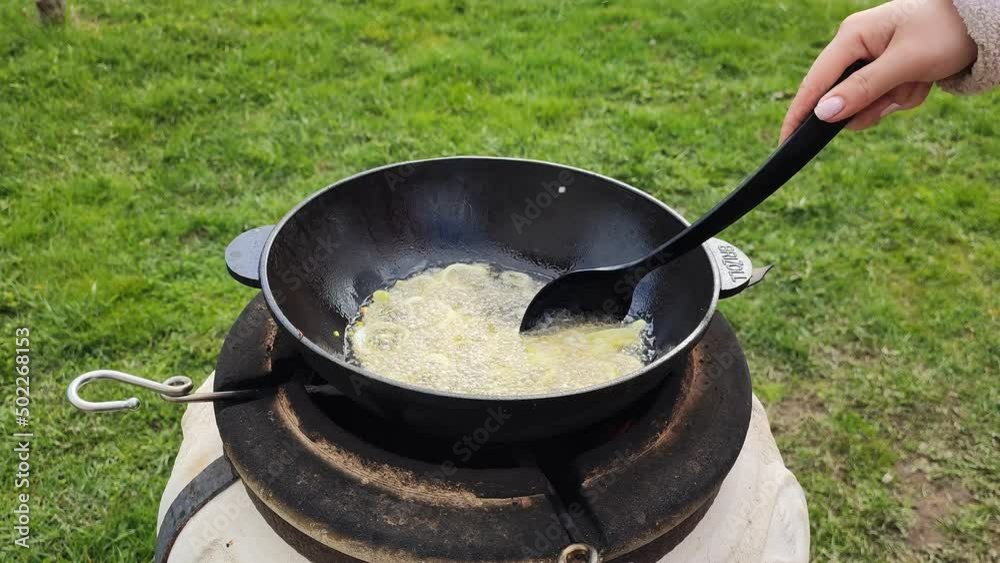 Cooking grilled onions in oil in pan. The cook girl mixes the food in the cauldron with her hand. 27 April 2022, Minsk, Belarus Cooking grilled onions in oil in pan. The cook girl mixes the food in the cauldron with her hand. 27 April 2022, Minsk, Belarus