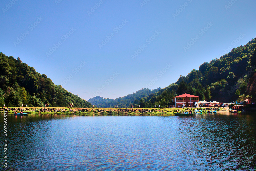presa o lago azul con montañas al rededor y cesped verde alrededor en villa del carbon estado de mexico