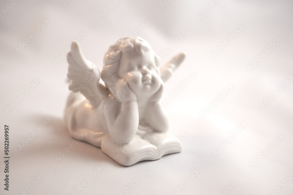 Porcelain angel with a book on a white surface Porcelain angel with a book on a white surface
