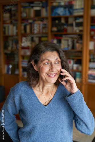 Smiling senior woman on the phone with library on background