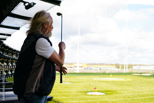 Senior man playing golf in modern golf location