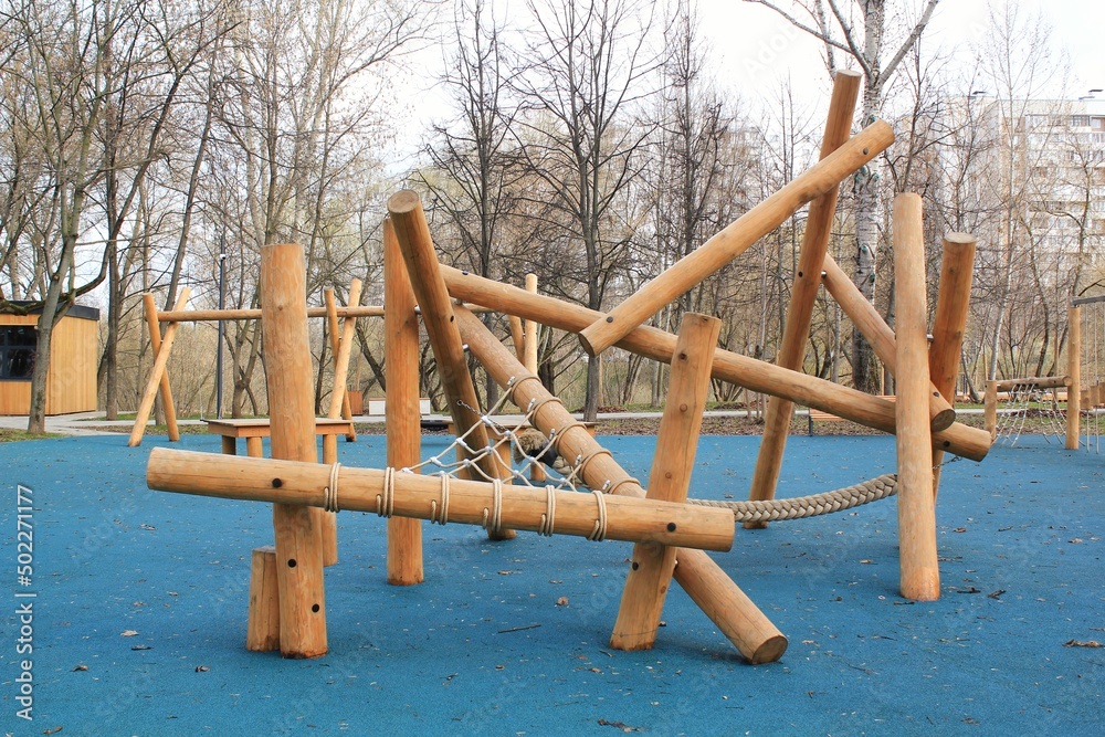 Outdoor modern children wooden playground in a public park of city. Eco-friendly lifestyle rest and childhood concept of safety environmentally infrastructure for kids. Outdoor modern children wooden playground in a public park of city. Eco-friendly lifestyle rest and childhood concept of safety environmentally infrastructure for kids.