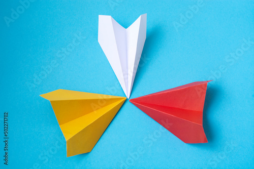 multicolored paper planes on a blue background. The concept of leadership  teamwork and courage.