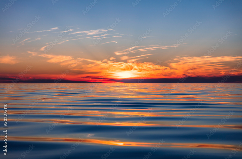 Beautiful summer evening sunset over calm waters of Georgian Bay in Wasaga Beach with reflections