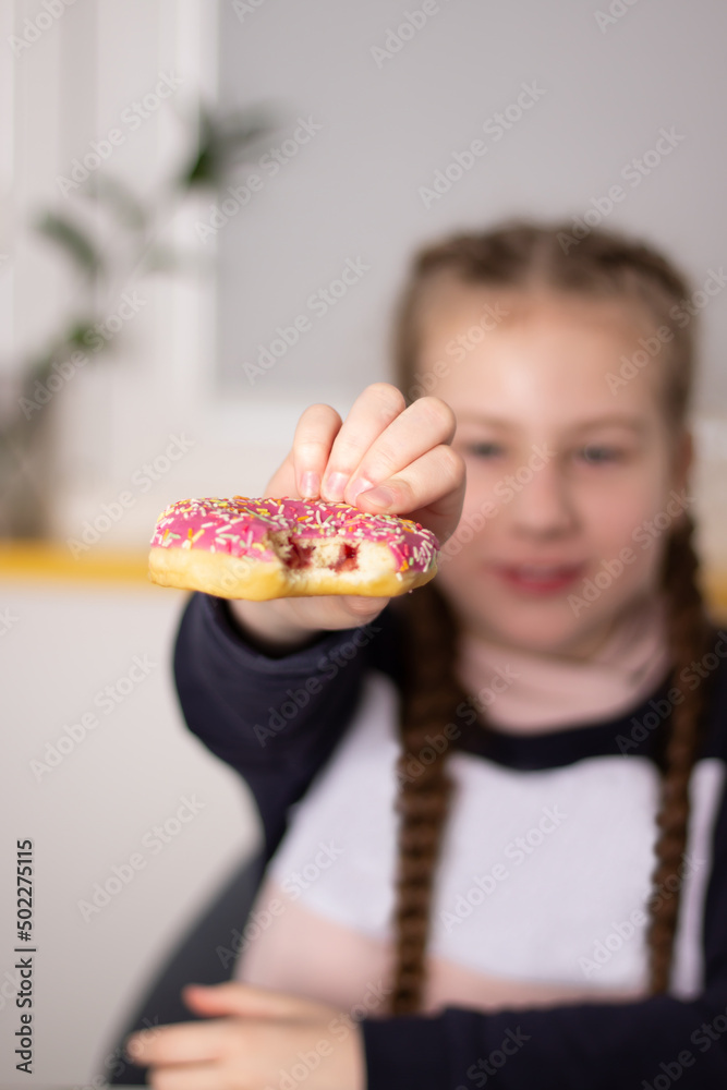 Close-up shot of a kid extending a donut towards the camera, focusing on the treat with a blurred background. Close-up shot of a kid extending a donut towards the camera, focusing on the treat with a blurred background.