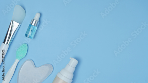 cosmetic accessories on a blue background. facial wash brush, gouache stone facial massager, skin care products close-up. pattern with cosmetics. top view, flat lay.