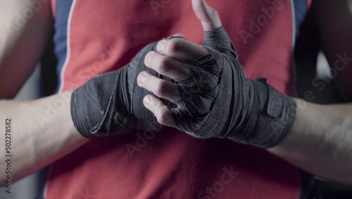 Man flexing his fists before a fight. Close-up of a young Thai boxer hands hemp ropes are wrapped before the fight or training