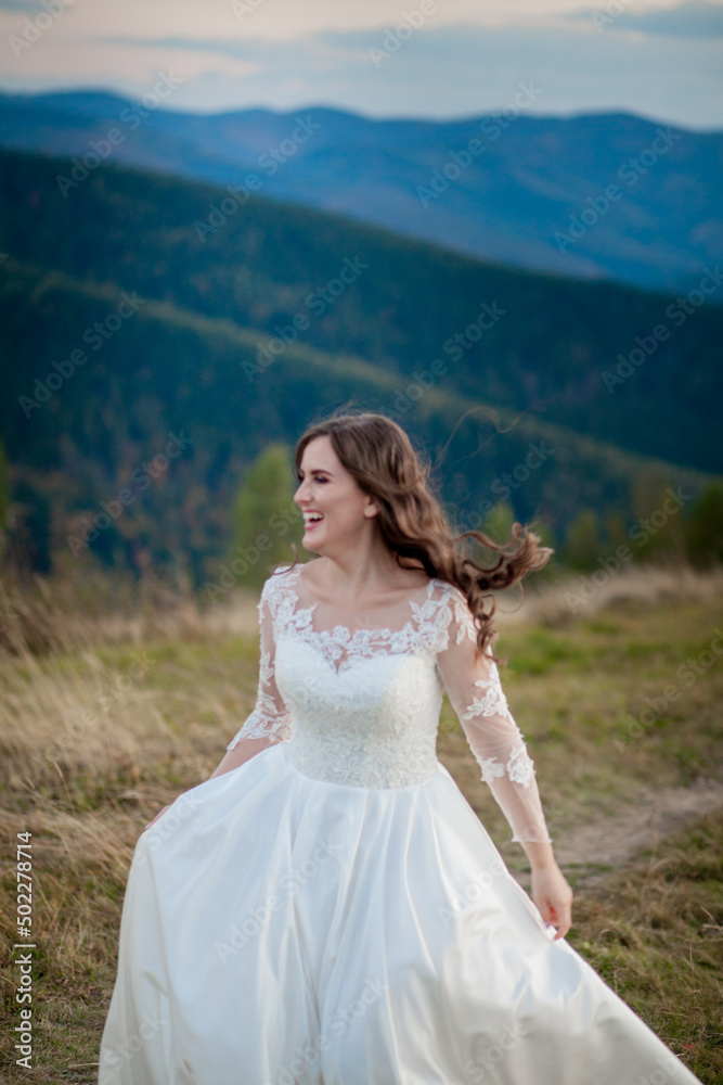 Beautiful wedding couple, bride and groom, in love on the background of mountains. The groom in a beautiful suit and the bride in a white luxury dress. Wedding couple is walking