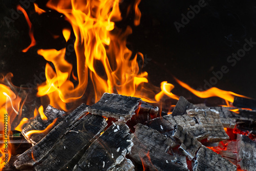 Bright orange flashes of fire from a bonfire on coals