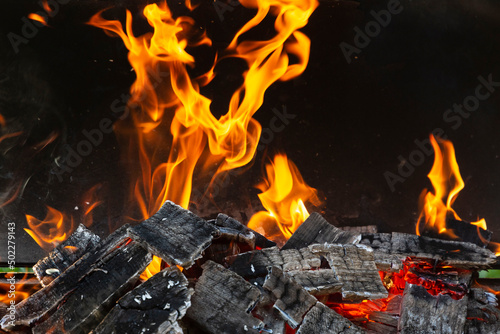 Bright orange flashes of fire from a bonfire on coals